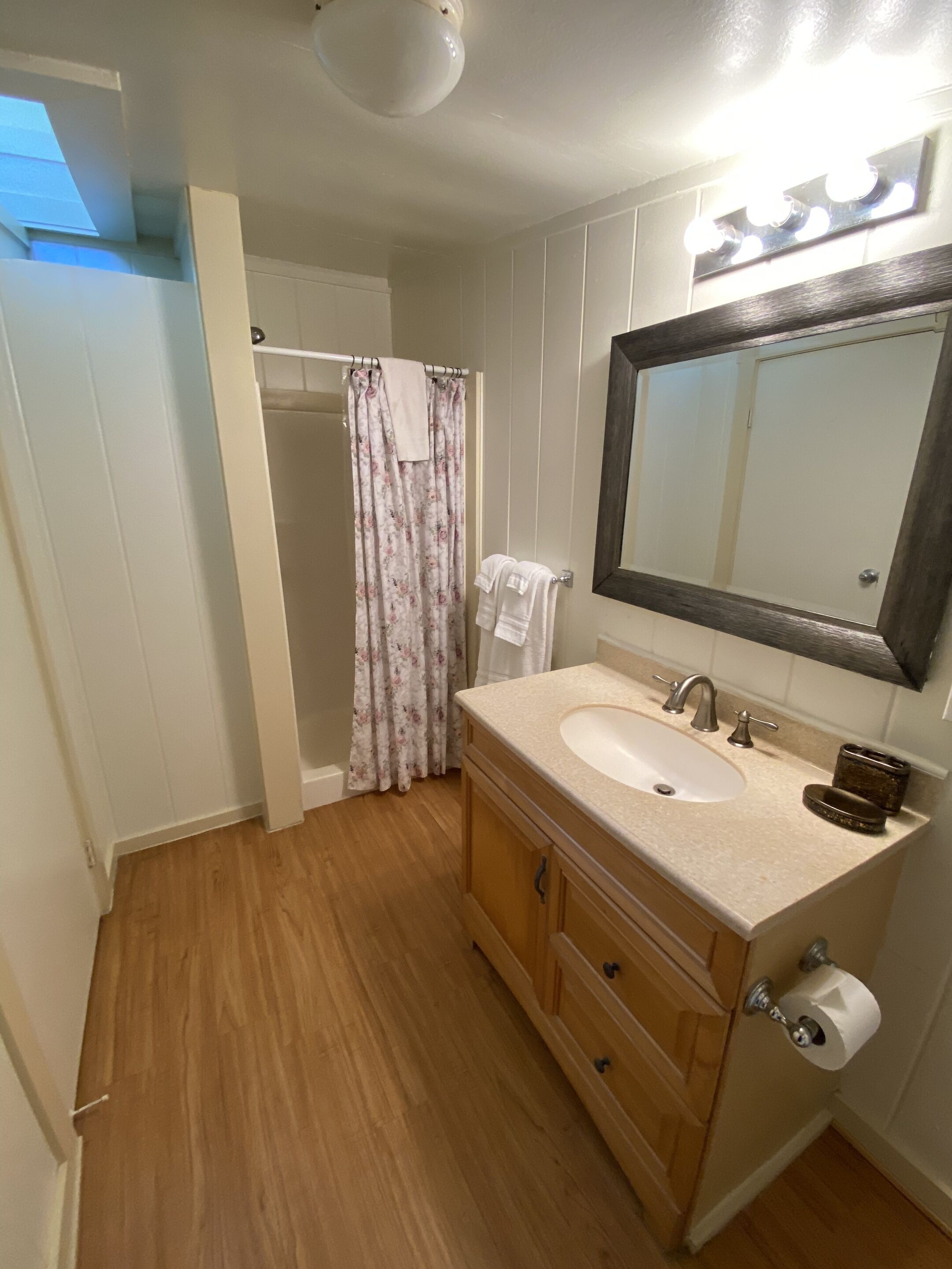 A bathroom with a wooden vanity, a sink, a mirror, and a shower curtain.