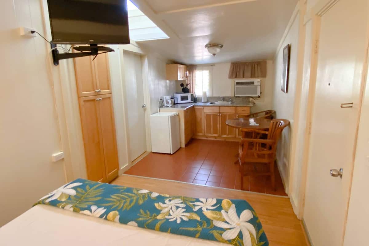 Habitación pequeña con cama, kitchenette y zona de comedor.