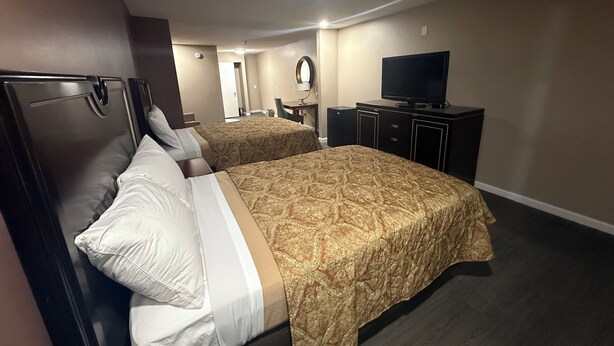 Una habitación de hotel con dos camas, televisión, escritorio y espejo.