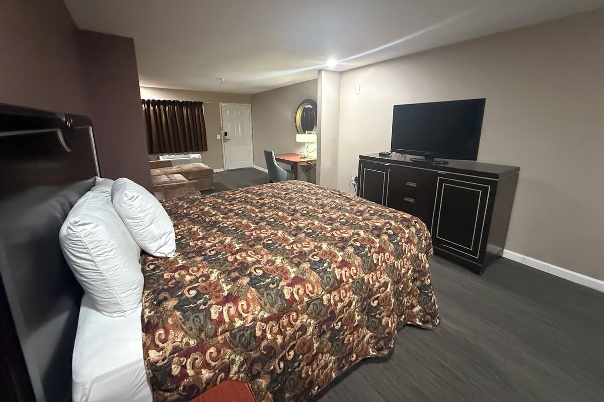 A hotel room with a bed, a TV, a desk, and a chair.