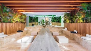 A modern indoor space with a long, central seating area, wooden paneling, and lush greenery. - Tulum City Apartments M-228 (Tulum)