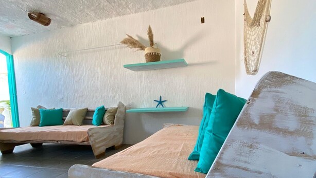 A rustic room with two wooden beds, a small shelf with decorative items, and a starfish decoration. - Pousada Cantinho Ossos (Búzios)