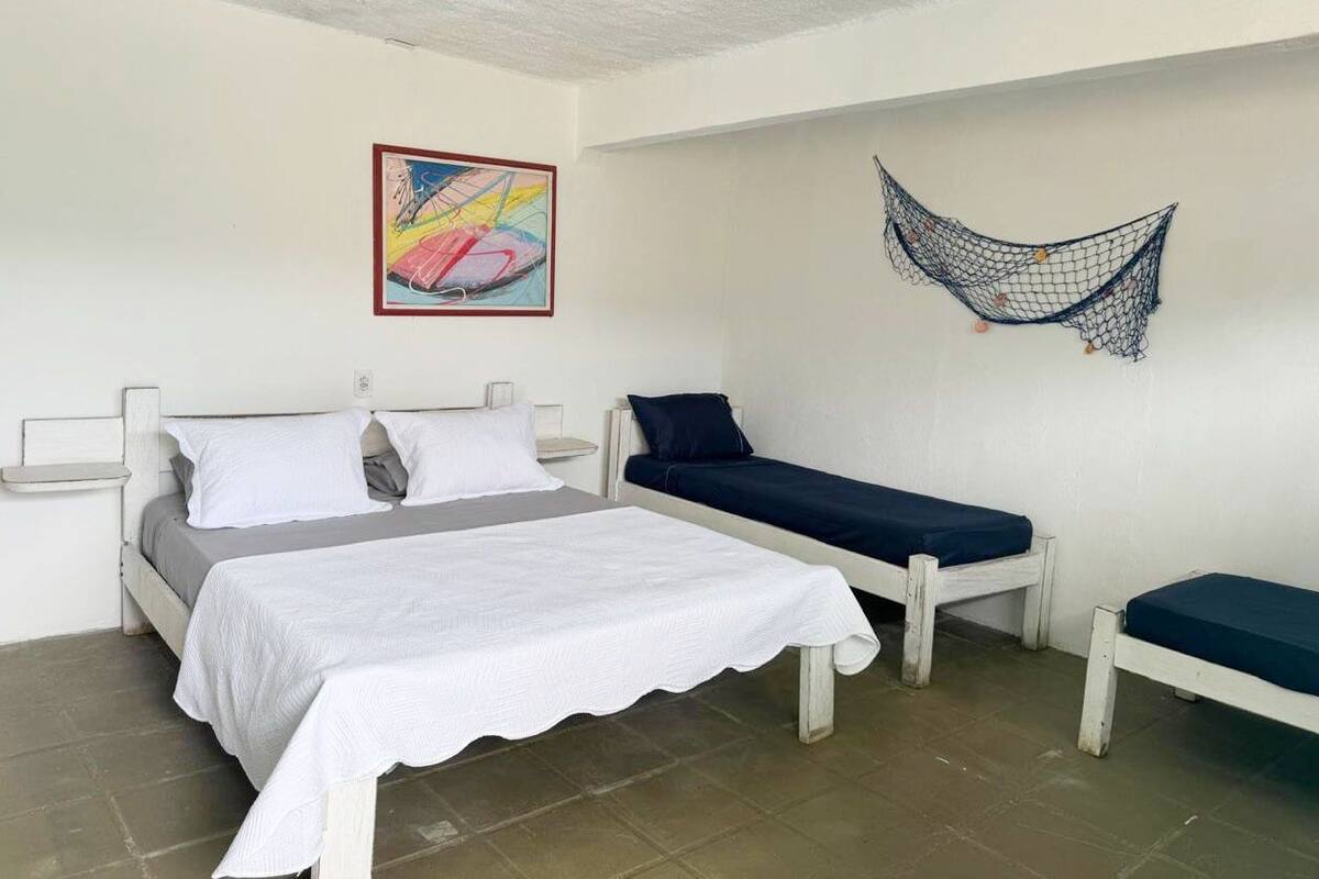 Ein Schlafzimmer mit einem Bett, einem zusätzlichen Bett, einer Hängematte und einem farbenfrohen abstrakten Gemälde an der Wand.