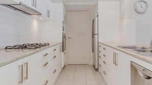 A modern kitchen with white cabinets, stainless steel appliances, and a tiled backsplash. - Ocean views from your spacious balcony at Seaside Escape Aria (Rockingham)