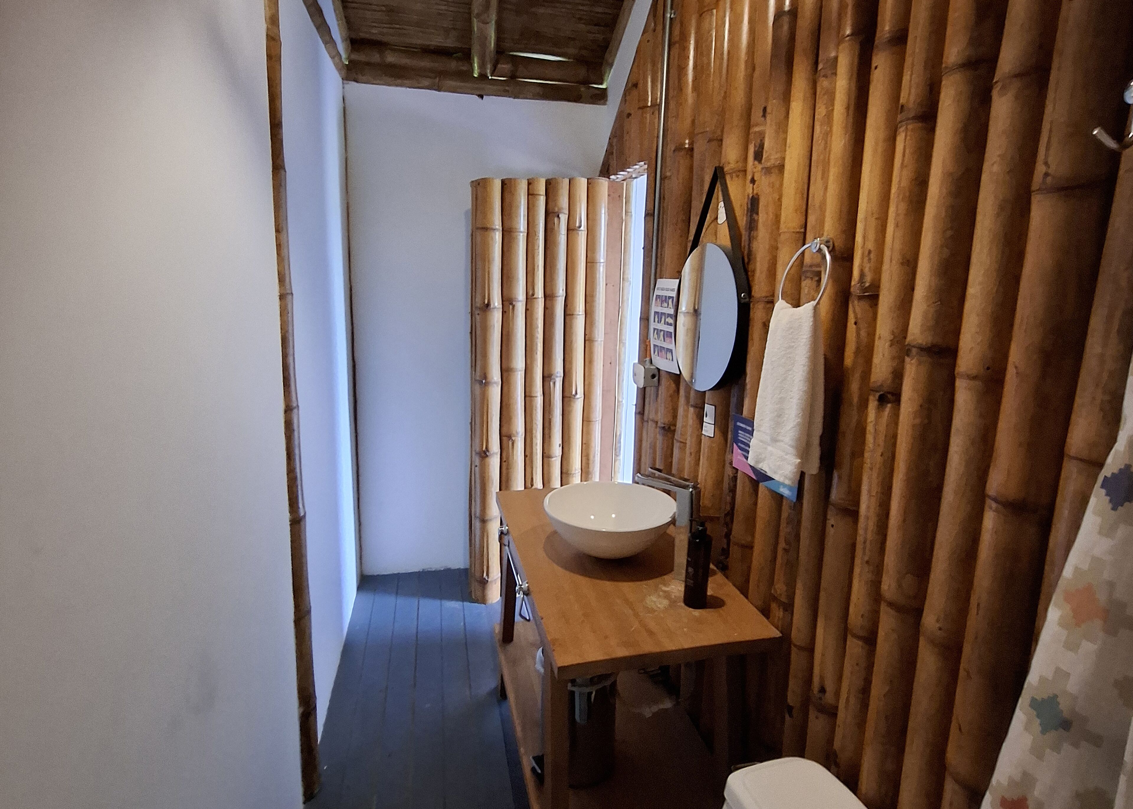 Un baño con pared de madera, un lavabo, un espejo y una toalla colgada en la pared.