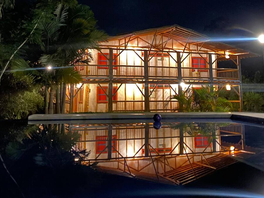 Un edificio de dos pisos con un balcón y una piscina delantera.