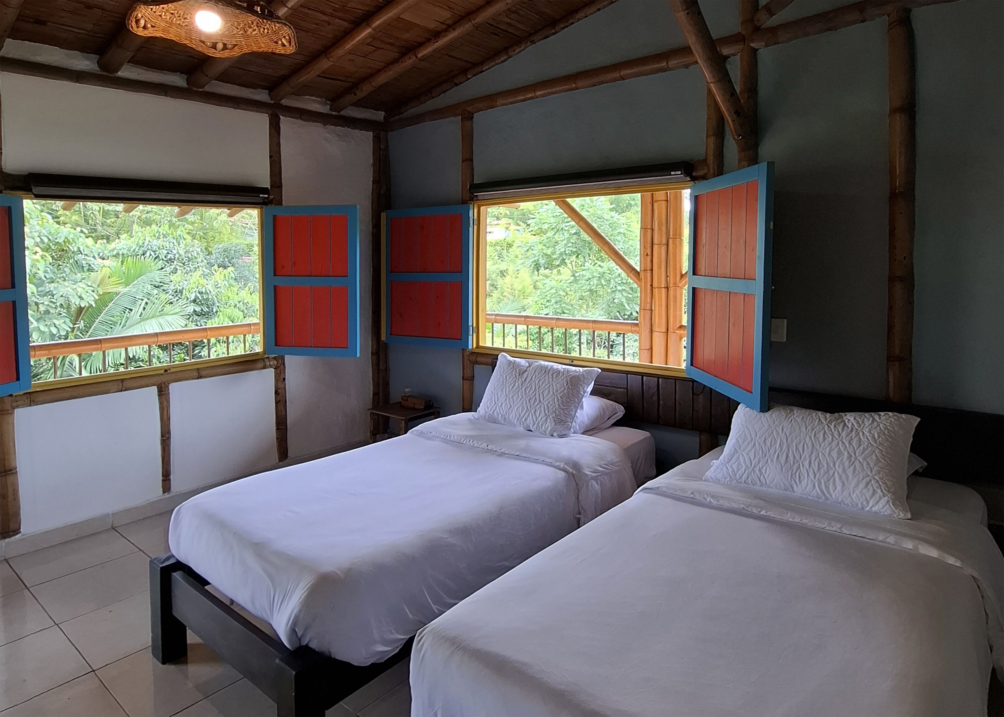A room with two beds, wooden beams, and windows with red shutters.