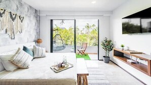 Een moderne slaapkamer met een bed, een televisie, een balkon en uitzicht op groen.