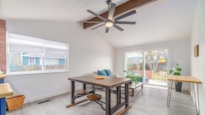 A spacious room with a large dining table, a ceiling fan, and a view of the outside.