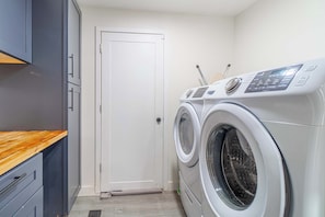 Un área de lavandería con lavadora y secadora, una encimera de madera y una puerta.
