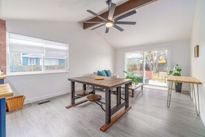 Una habitación amplia con una gran mesa de comedor, un ventilador de techo y vistas al exterior.