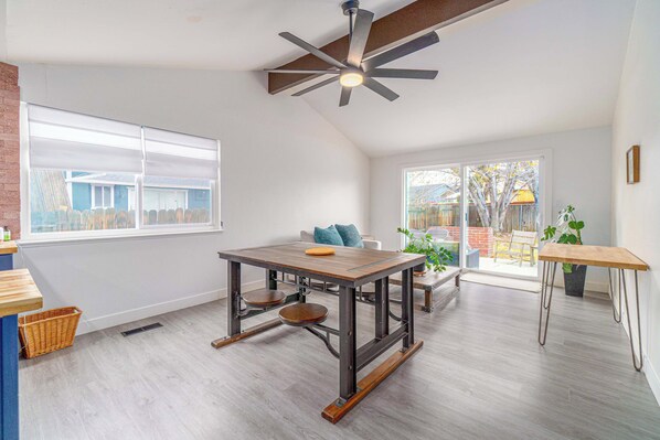 Una habitación amplia con una gran mesa de comedor, un ventilador de techo y vistas al exterior.