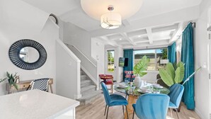 A modern dining area with a staircase, a dining table set for four, and a large plant. - Jungle House | AirCon | Sleeps 8 | Near WEM & DT! (Edmonton)
