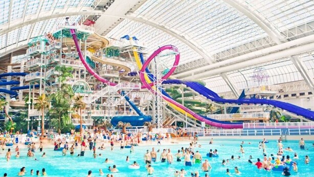 Un parque acuático interior grande con múltiples toboganes y piscinas.