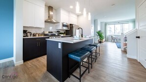 A modern kitchen with a central island, stainless steel appliances, and pendant lighting.