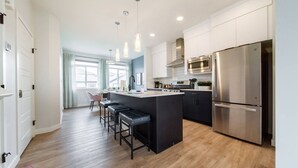 A modern kitchen with a central island, stainless steel appliances, and a bar seating area.