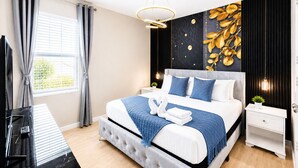 A modern bedroom with a bed, a TV, a nightstand, and a wall with a leaf pattern.