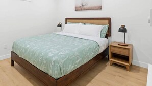Une chambre à coucher avec un lit en bois, une table de chevet, une lampe et un tableau au mur.