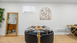 Un coin repas avec une table en verre, des chaises noires et un meuble en bois.