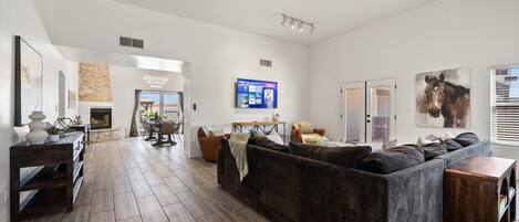 A spacious living area with a dark-colored sofa, a wooden coffee table, and a ceiling fan.