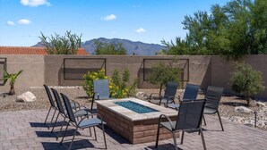 Eine Terrasse im Freien mit Feuerstelle, Sitzgelegenheiten und Blick auf die Berge.