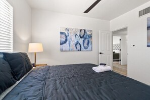 A bedroom with a large bed, a painting on the wall, and a door leading to another room. - 4BR Home w/ Mountain Views, Pool, Spa, Firepit & Gazebo (Tucson)
