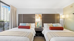 A hotel room with two beds, a nightstand with a lamp, a view of a cityscape, and a large window with curtains. - NEW! Stylish and Cozy Studio near Waikiki Beach! (Honolulu)