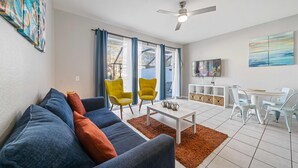 A modern living room with a sofa, two yellow chairs, a coffee table, and a dining area with a table and chairs. - Gorgeous Vacation Home With Pool Close To Disney (Kissimmee)