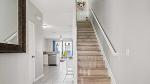 A staircase leading to a second floor, a kitchen area with a dishwasher, and a dining area with a yellow chair. - Gorgeous Vacation Home With Pool Close To Disney (Kissimmee)