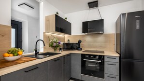 A modern kitchen with a black refrigerator, a built-in oven, and a microwave. There is a wooden countertop and a sink with a black faucet. - 1 bedroom cozy home in Hreljin (Hreljin)