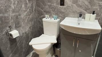 A modern bathroom with a marble floor, a toilet, a sink, and a mirror.