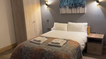 Un dormitorio con cama, armario, mesita de noche y un cuadro en la pared.