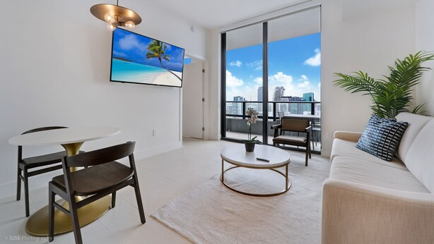 Ein modernes Wohnzimmer mit Essbereich, einem großen Fenster und Stadtblick sowie einer Deckenleuchte.