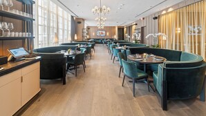 En moderne restaurant med turkise siddebænke, trægulv og en lang disk med en digital menuskærm.