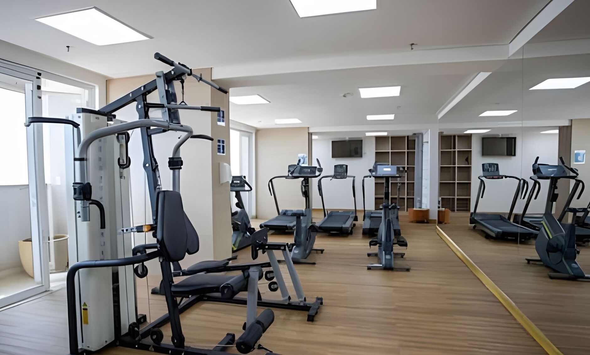 Et fitnesscenter med forskellig træningsudstyr, herunder løbebånd, elliptiske træningsmaskiner og styrkemaskiner.