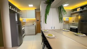 Una cocina moderna con una isla central, electrodomésticos integrados y una planta colgante.