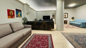 Un salon avec un canapé, une table basse, un téléviseur et un divan bleu.