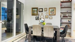 Un coin repas avec une table et des chaises, des tableaux encadrés au mur et une bibliothèque.