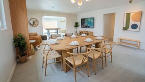 A modern dining area with a round table set for six, surrounded by six wooden chairs.