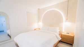 A minimalist bedroom with a large bed, bedside tables, a mirror, and a unique ceiling light fixture.