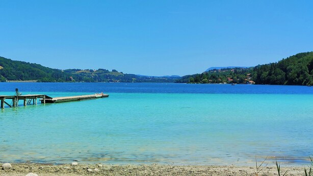 A clear lake with a wooden pier extending into the water.
