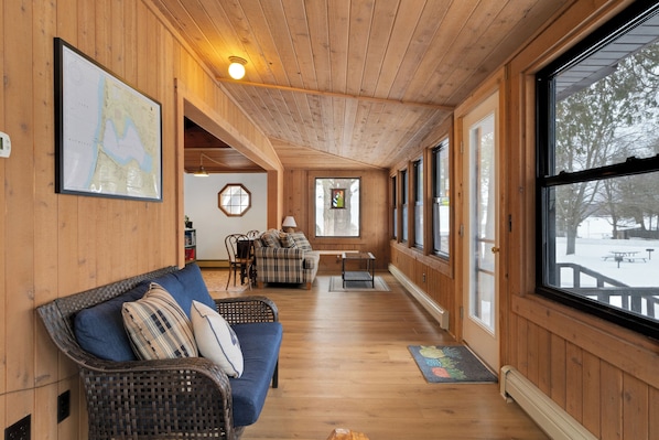 A wooden interior with a sofa, a map on the wall, and large windows.