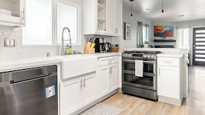 Cocina moderna con armarios blancos, electrodomésticos de acero inoxidable y una estufa negra.