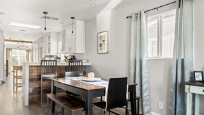 Una cocina moderna con armarios blancos, una isla de madera e iluminación colgante.