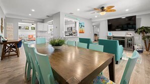 A modern kitchen with white cabinets, a dining area with a wooden table and teal chairs, and a ceiling fan. - Spacious and Short Drive to Beach (St. Petersburg)