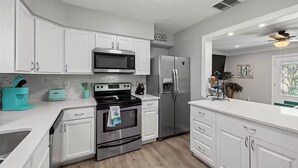 A modern kitchen with white cabinetry, stainless steel appliances, and a teal coffee maker. - Spacious and Short Drive to Beach (St. Petersburg)