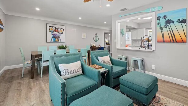 A dining area with teal upholstered chairs, a wooden table, and a ceiling fan. - Spacious and Short Drive to Beach (St. Petersburg)
