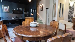 A dining area with a round wooden table, leather chairs, and a white centerpiece. - L' Appart 1925 - REIMS (REIMS)