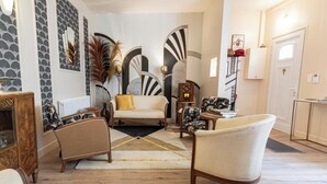 A modern living room with a sofa, armchairs, a coffee table, and decorative elements like wall art and a fireplace. - L' Appart 1925 - REIMS (REIMS)