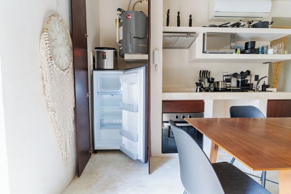 A compact kitchen with a refrigerator, microwave, and stove.